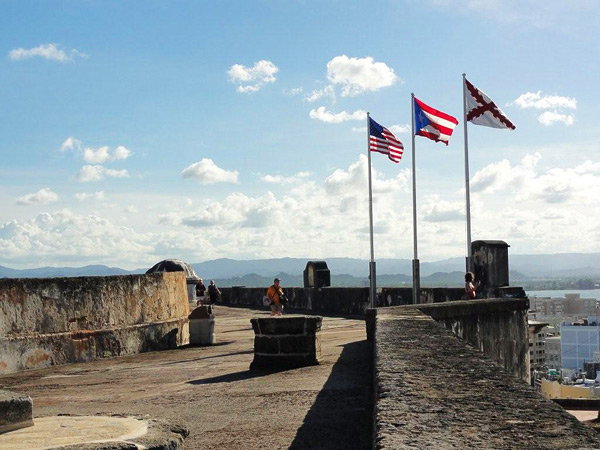 Tres banderas ondean en el Fuerte de San Cristóbal, en San Juan: la de Estados Unidos, la del Estado asociado de Puerto Rico y la Cruz de Borgoña, símbolo esta última de los tres siglos de época virreinal en que Puerto Rico estuvo unido políticamente al resto de Hispanoamérica, bajo la Corona española.